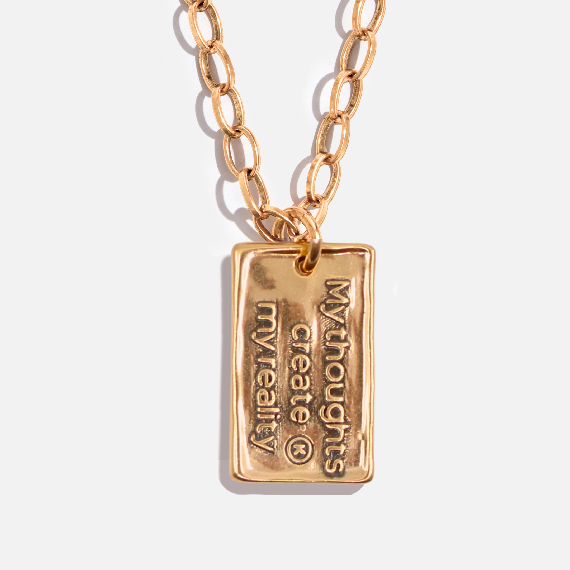 Gold necklace with a rectangular pendant on a light background