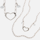 Two long chain necklaces with open heart pendants and crystal quartz accents, one with a gold-tone heart and clear quartz, and the other with a silver-tone heart and clear quartz.