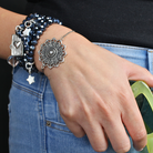 Close-up of a hand wearing multiple bracelets with decorative charms on a dark background