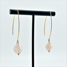 A person wearing small stone drop earrings with a V-shape wire design in a colorless setting.