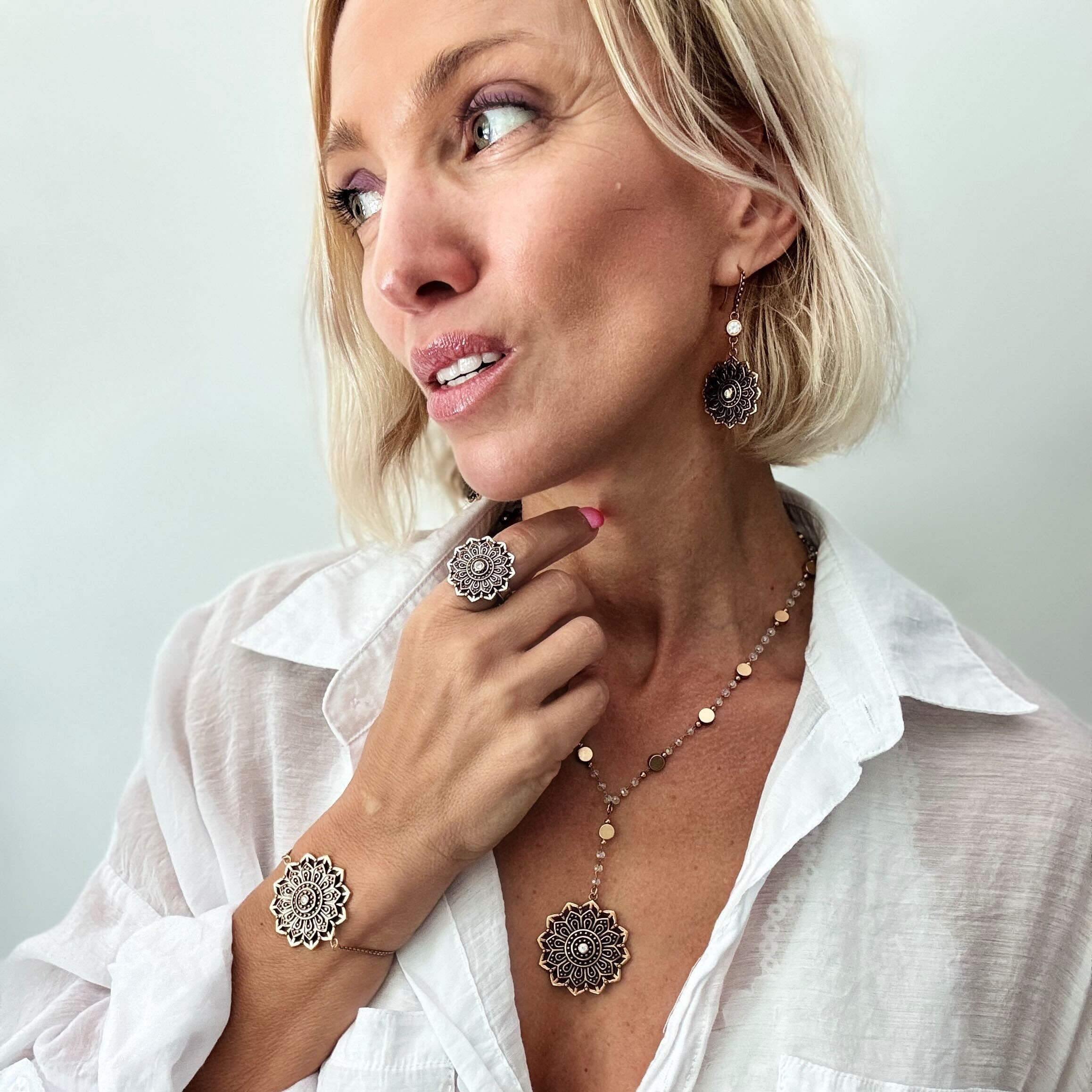 Woman wearing jewelry including a necklace, bracelet, and ring against a plain background