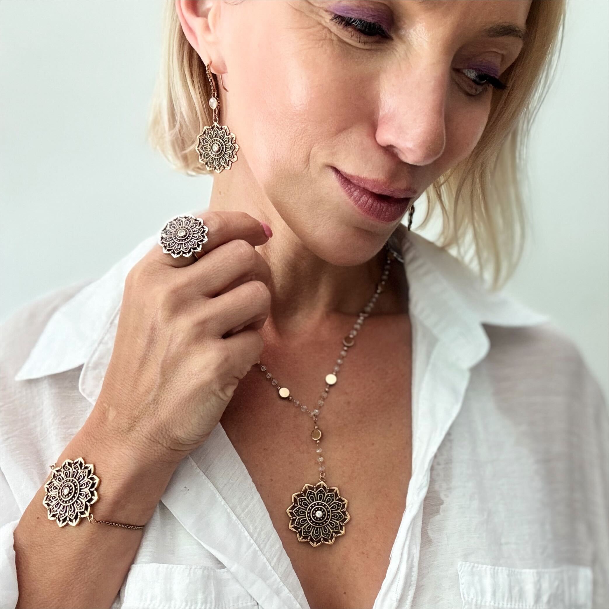 Woman wearing silver jewelry including earrings, ring, and necklace on a white background