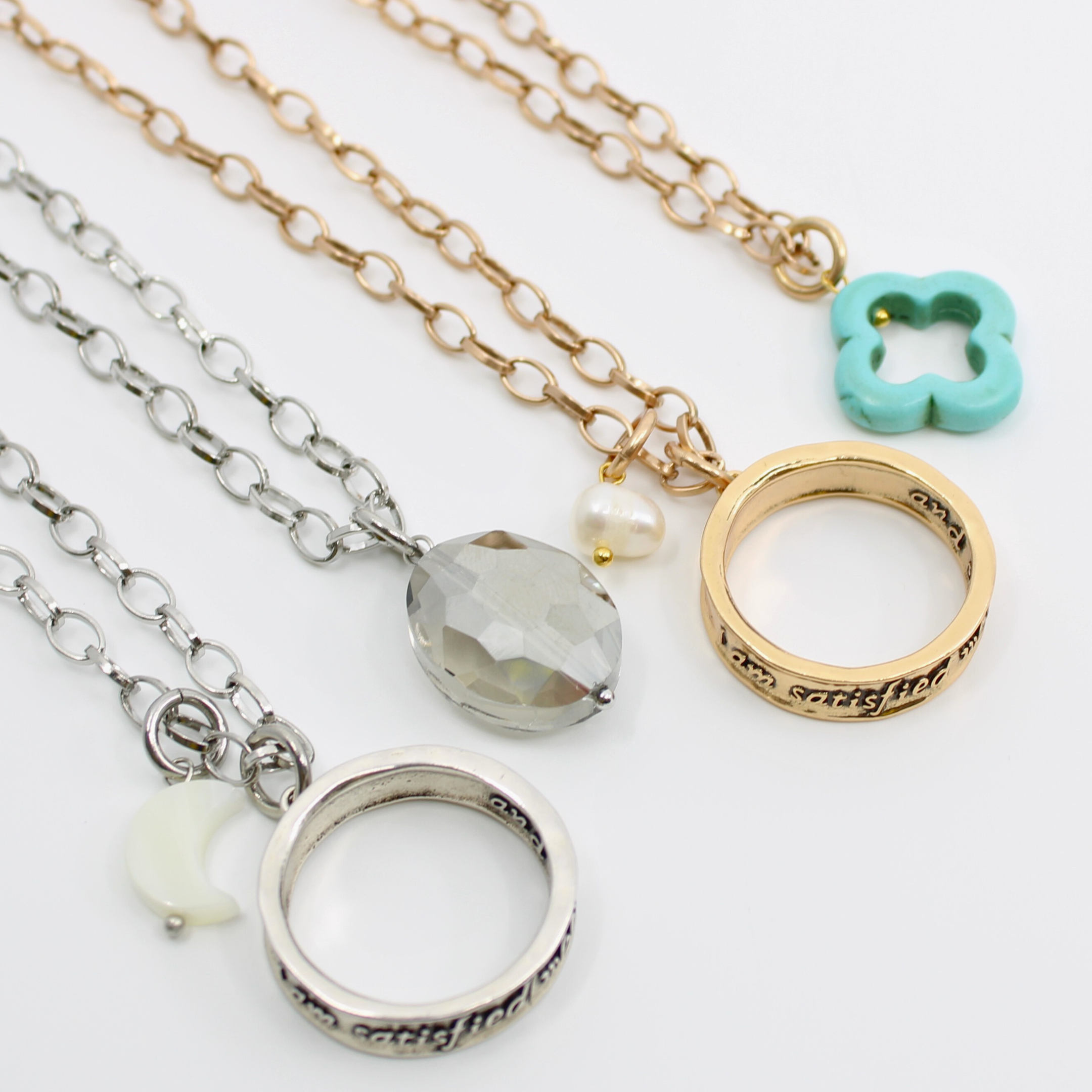 A collection of necklaces with stainless steel chains and various charms including a crystal, a pearl, and a clover.