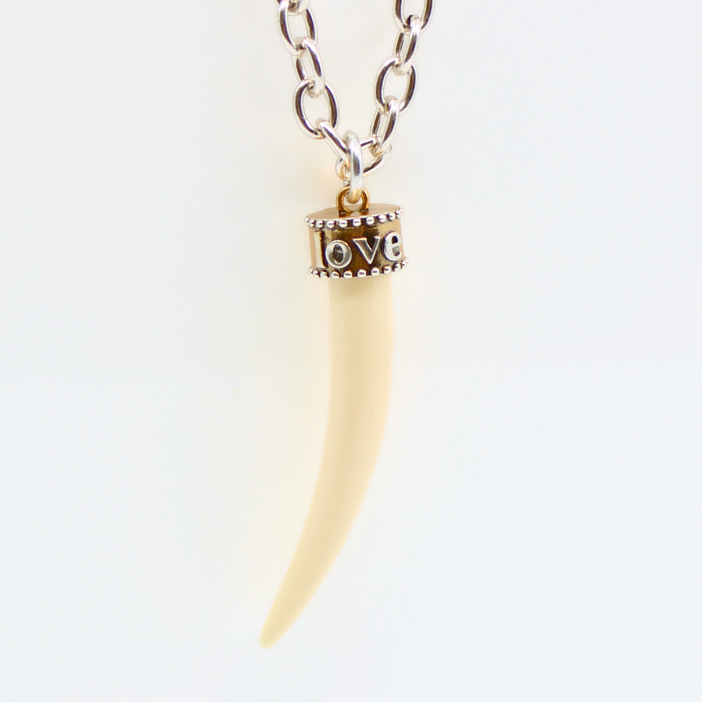 tusk-shaped pendants, crafted from synthetic polymer, hang gracefully from silver chain necklace displayed on a white background.