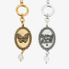 Two keychains, one gold with a butterfly design and the other silver with an inspirational quote, on a white background.