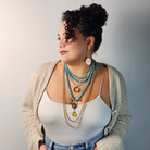 Woman wearing multiple necklaces with a neutral background