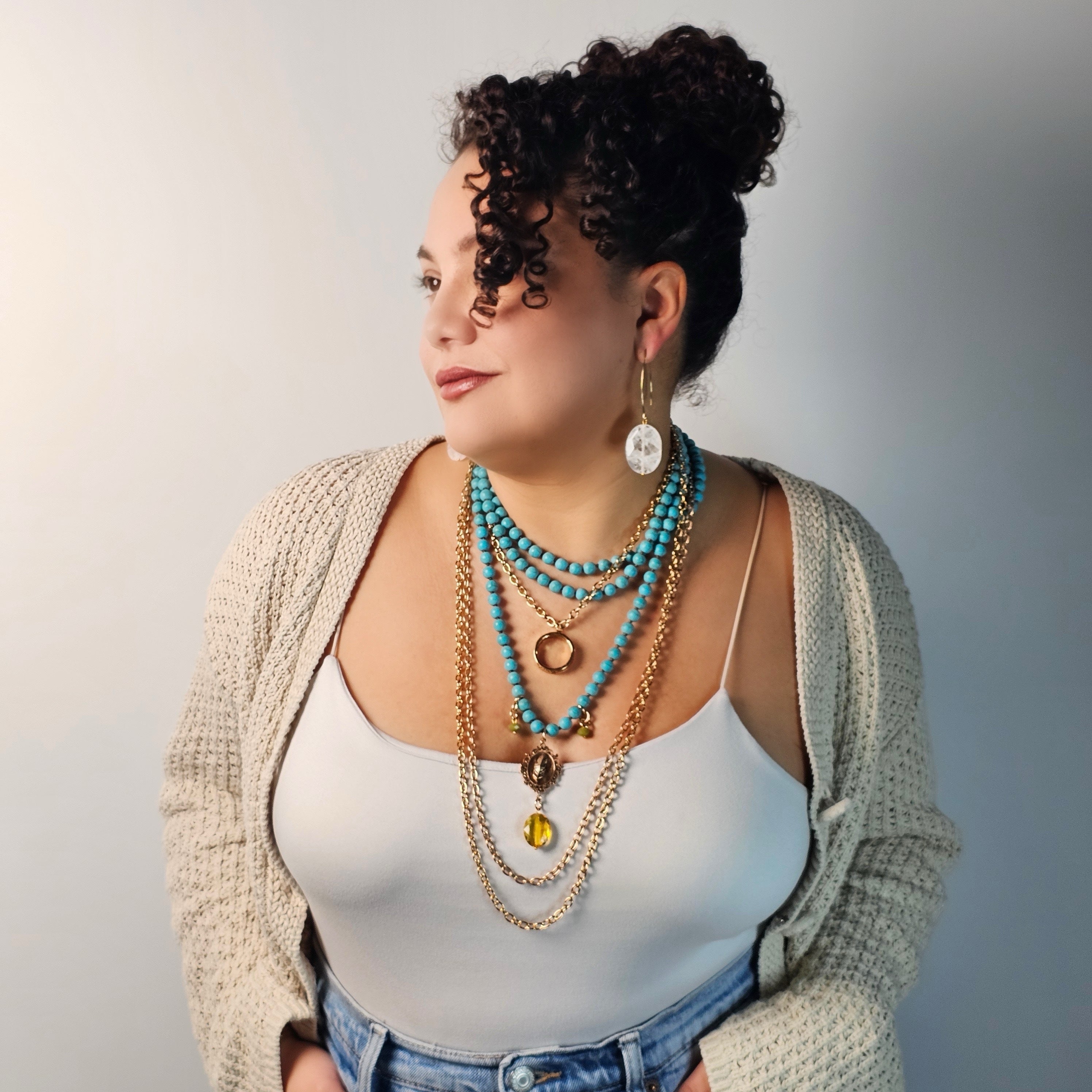 Woman wearing multiple necklaces with a neutral background