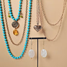 Jewelry set with turquoise beaded necklaces and heart pendant on a beige background