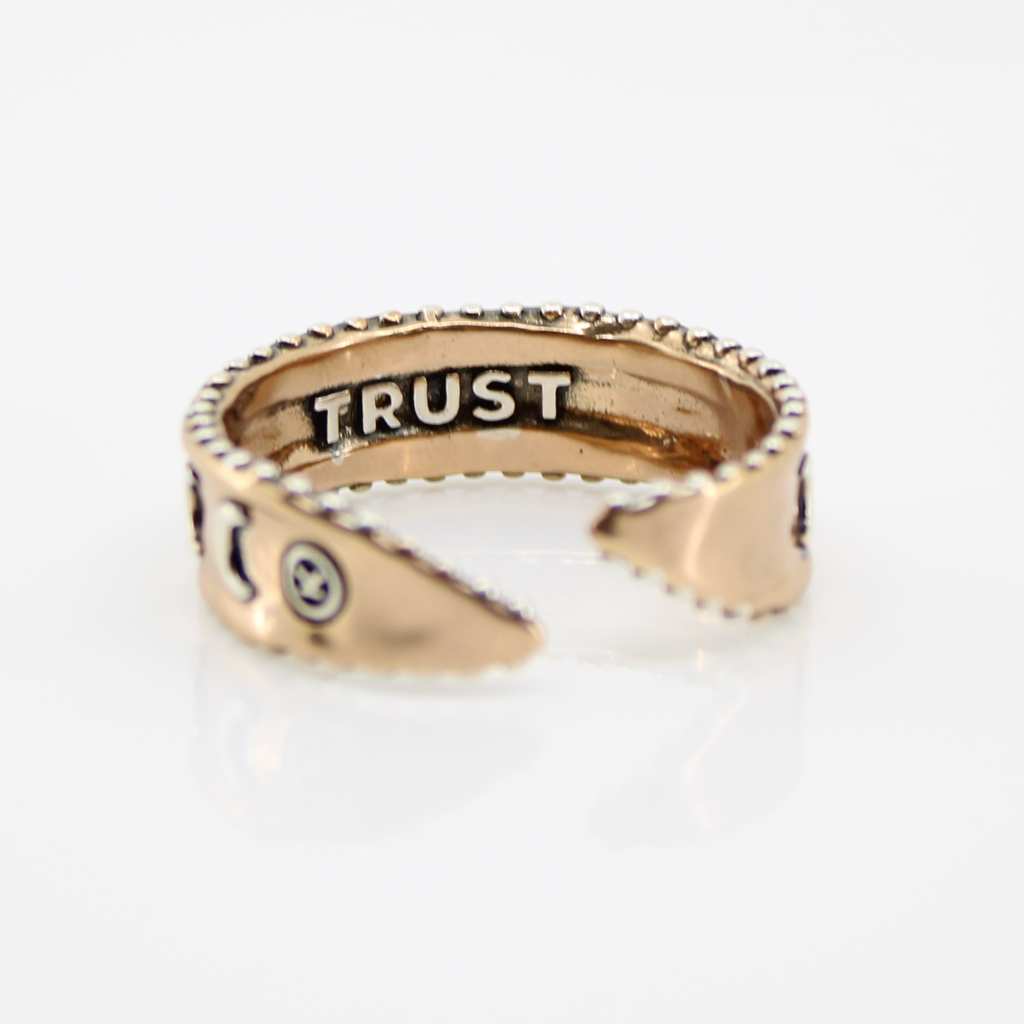 mixed-metal rings with crescent moon designs and TRUST engraved inside, each featuring adjustable bands, are shown from different angles.