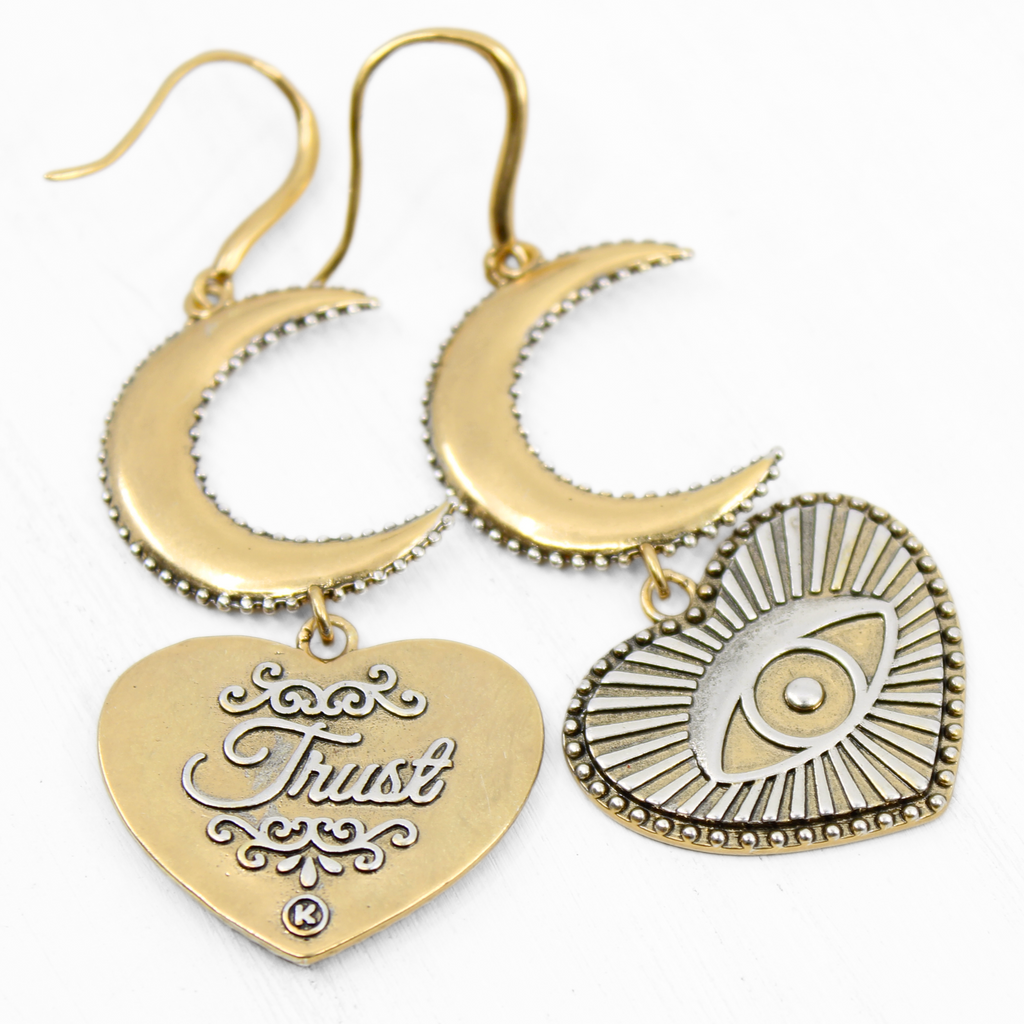 Gold earrings with crescent moons and heart-shaped pendants featuring eye designs, crafted in a mixed metal design. The pieces elegantly suspend from French ear wires, creating a captivating composite drop earring effect.