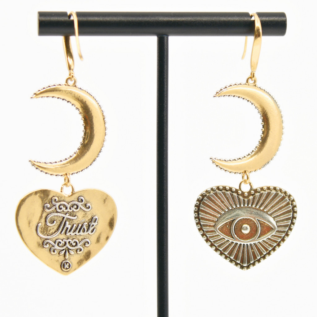 Gold earrings with crescent moons and heart-shaped pendants featuring eye designs, crafted in a mixed metal design. The pieces elegantly suspend from French ear wires, creating a captivating composite drop earring effect.