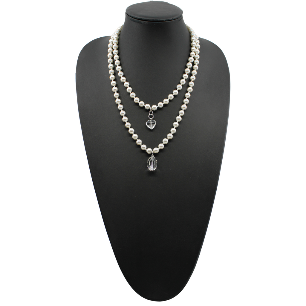 white layering pearl necklace
Strings of white pearls with quartz heart-shaped pendants lie on a light surface. These pearl necklaces are connected to the pendants using metal clasps in gold or silver finish options.