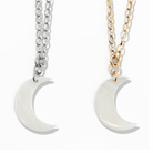Two moon-shaped pendants on chains, one silver and one gold, on a white background.
