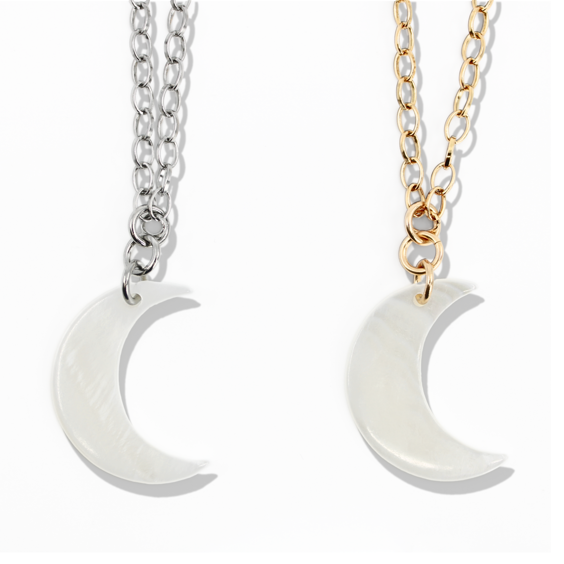Two moon-shaped pendants on chains, one silver and one gold, on a white background.